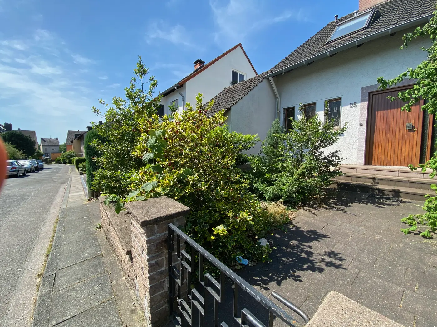 Ruhige Straße im Sommer, Vorgarten mit Hecke und Hauseingang